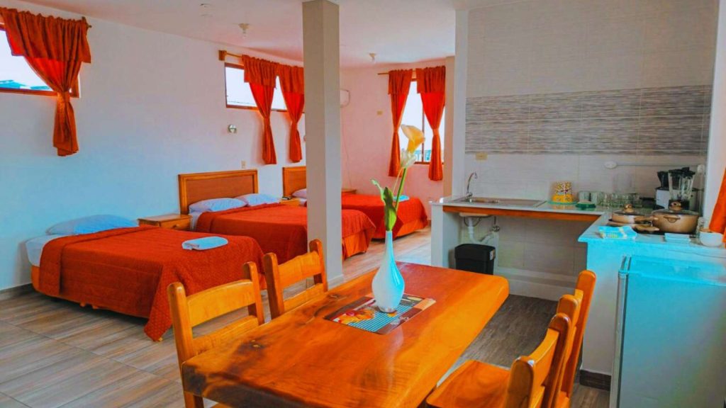 Vista del comedor y la cocina integrada en la Suite 23 en Central Suites, junto a las camas.