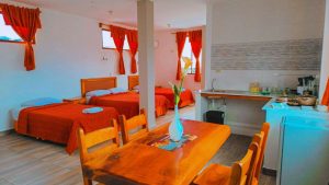 Vista del comedor y la cocina integrada en la Suite 23 en Central Suites, junto a las camas.